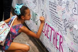 Girl writing on Grenfell memorial wall
