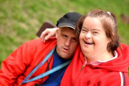 A young woman and man with Downs Syndrome hug and smile