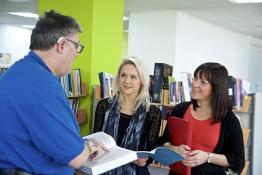 Hearing impaired man talking to two women in a library