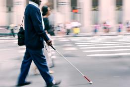 Visually impaired main crossing a road using a walking stick