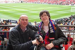 A football fan in a wheelchair with their carer at Wembley Stadium