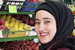 A woman wearing a headscarf working in a grocer's shop