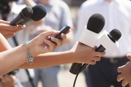 Hands holding microphones and tape recorders at a press conference