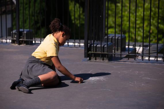 school student writes with chalk on the playground floor 